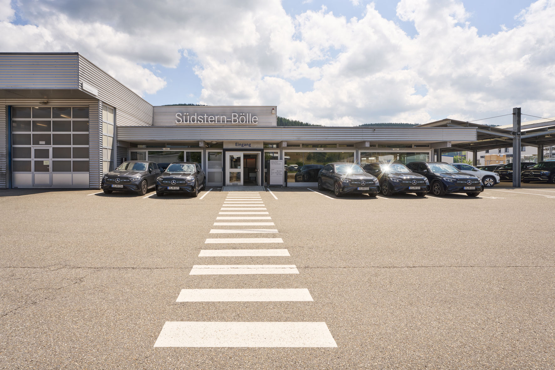 Südstern - Bölle ist Mercedes-Benz Partner. Hier zu sehen ist der Südstern - Bölle Standort Titisee-Neustadt – mit Blick auf den Parkplatz und mehreren wehenden Flaggen